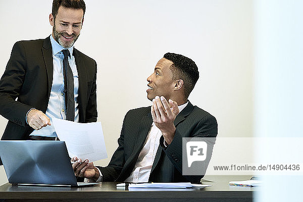 Businessmen discussing document at desk in office