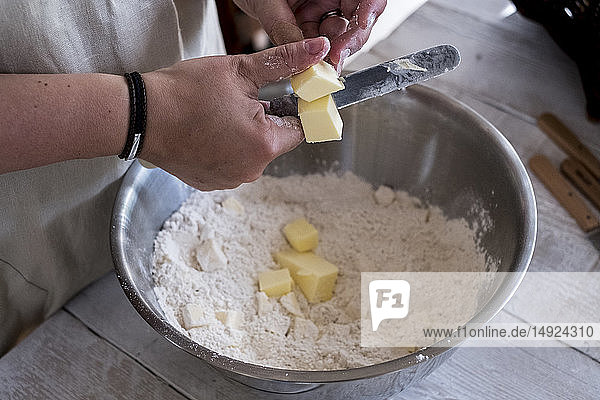 High angle close up of person mixing butter and flour for a crumble in metal bowl.