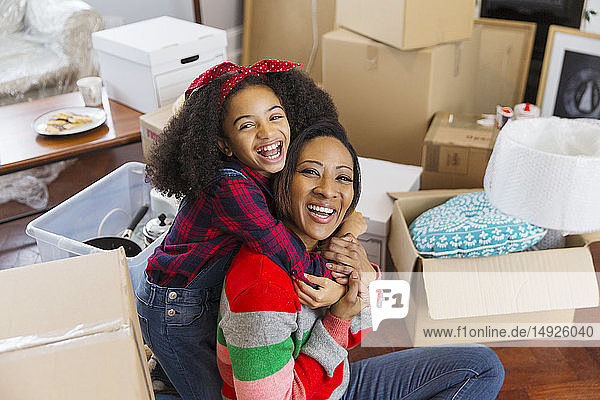 Porträt glückliche  begeisterte Mutter und Tochter  die sich zwischen Kisten umarmen  Umzug