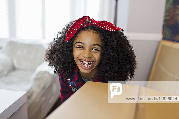 Porträt glückliches Mädchen hinter Karton  Umzug in neues Haus