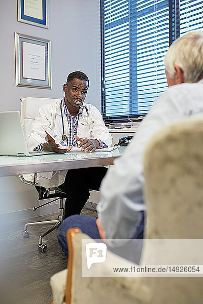 Arzt mit digitalem Tablet im Gespräch mit einem Patienten in einer Arztpraxis
