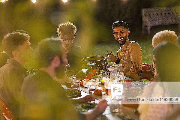 Fröhliche Freunde beim Abendessen auf einer Gartenparty