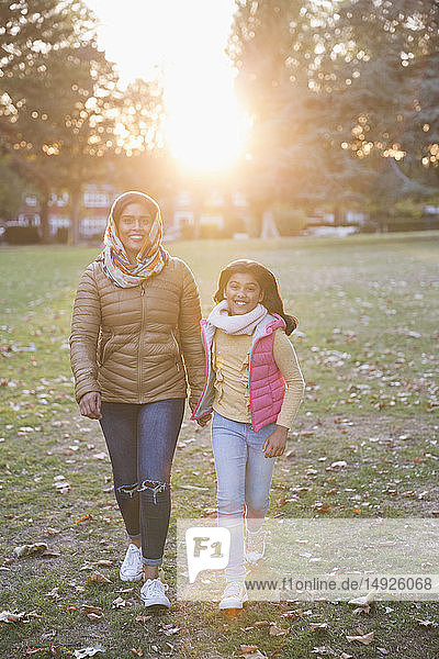 Porträt glückliche muslimische Mutter und Tochter zu Fuß in sonnigen Herbst Park