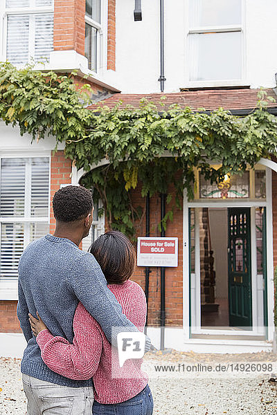 Glückliches Paar  das sich vor seinem neuen Haus umarmt