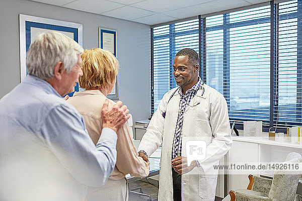 Doctor shaking hands with senior couple in doctors office