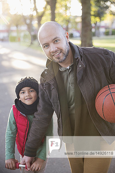 Portrait father and son with basketball in autumn park