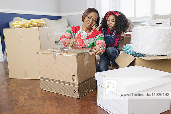 Mother and daughter taping moving boxes  moving house