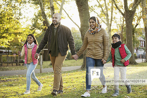 Muslim family holding hands  walking in autumn park