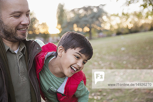 Glücklicher Vater und Sohn spielen im Herbst im Park
