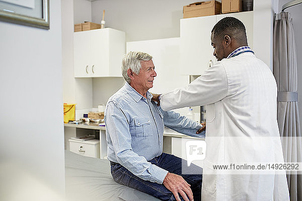 Male doctor examining senior patient in clinic examination room
