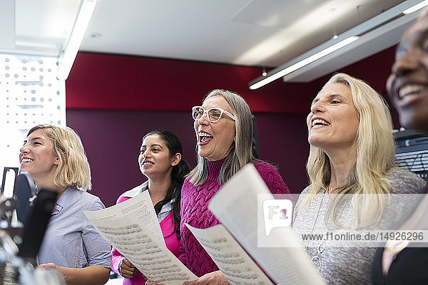 Womens choir with sheet music singing in music recording studio