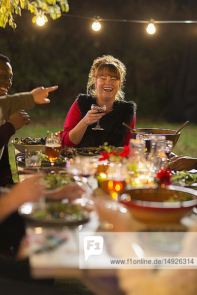Glückliche Frau lacht  genießt Abendessen Gartenparty mit Freunden