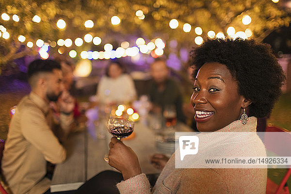 Porträt einer glücklichen Frau  die Wein trinkt und das Abendessen auf einer Gartenparty genießt