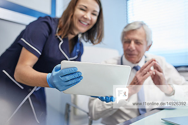 Arzt und Krankenschwester verwenden digitales Tablet in einer Arztpraxis