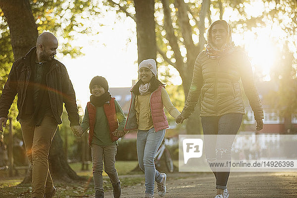 Happy family holding hands  walking in sunny autumn park