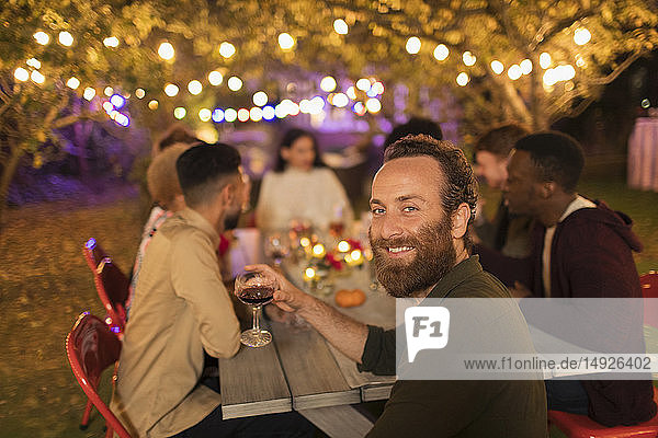 Porträt selbstbewusster Mann  der Wein trinkt und das Abendessen auf einer Gartenparty genießt