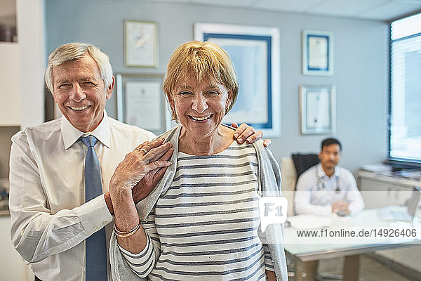 Portrait happy senior couple leaving clinic doctors office