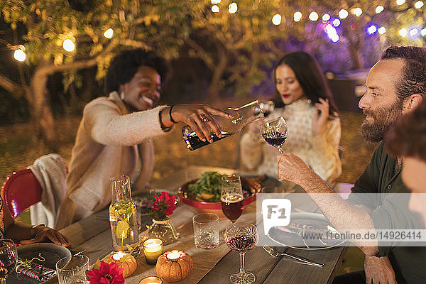 Freunde schenken Wein ein und trinken ihn  genießen das Abendessen auf einer Gartenparty