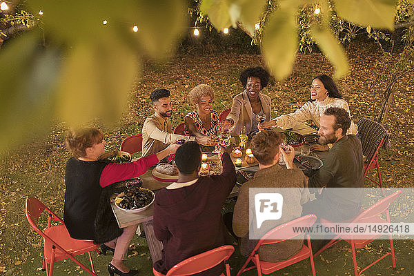 Freunde stoßen mit Wein an und genießen das Abendessen auf einer Gartenparty