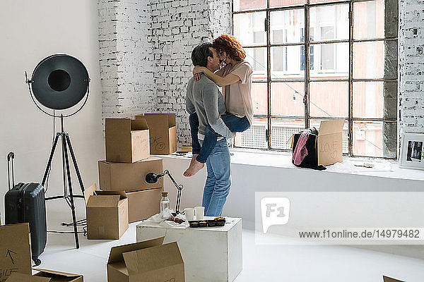 Romantisches Paar zieht in eine Wohnung im Industriestil Frau rittlings auf ihrem Freund der sich küsst