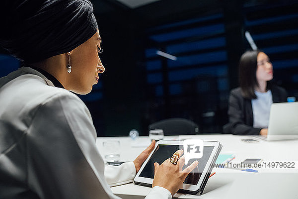 Geschäftsfrau verwendet digitales Tablett während einer Büropräsentation  Blick über die Schulter