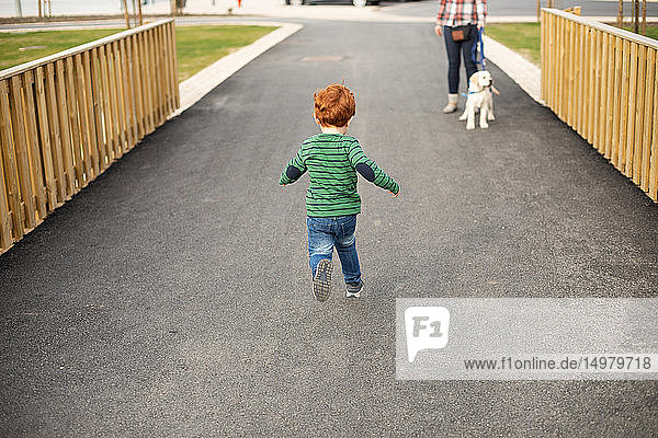 Boy running towards mother and pet puppy
