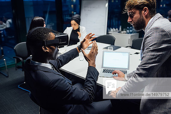 Geschäftsmann blickt während eines Konferenztischgesprächs durch ein Virtual-Reality-Headset