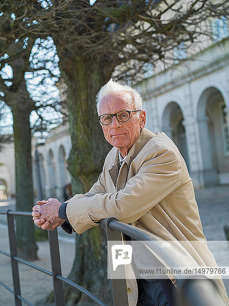 Älterer Mann im Regenmantel  der sich an die Stadtgeländer lehnt  Kopenhagen  Hovedstaden  Dänemark