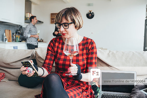 Woman using smartphone at party  friends talking in background