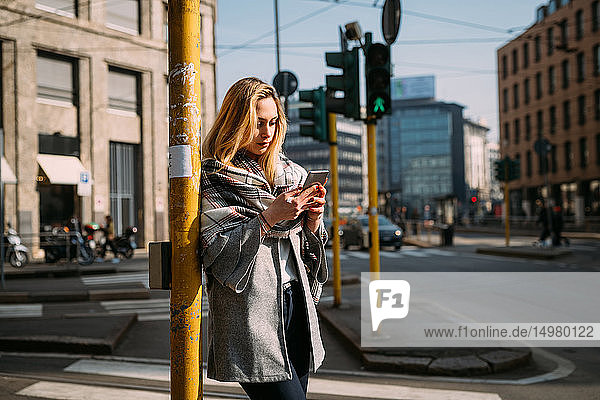 Junge Touristin schaut auf Smartphone an der Straßenbahnhaltestelle  Mailand  Italien