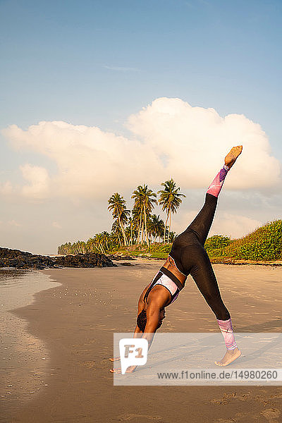 Woman practising yoga on beach