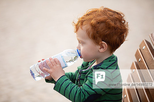 Boy drinking water on park bench