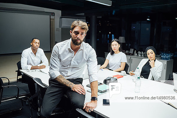 Mid adult businessman in front of team at conference table meeting  portrait
