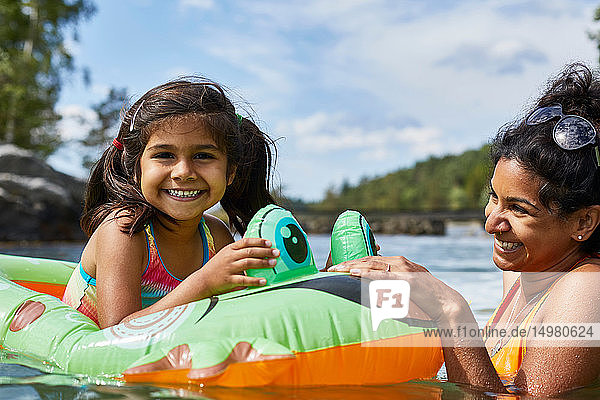 Mutter spielt mit Tochter auf aufblasbarem Frosch im See