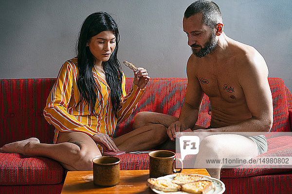 Hipster-Paar spielt Karten und frühstückt auf dem Sofa