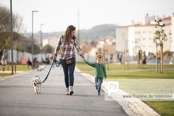 Mother and son walking with pet puppy on quiet road