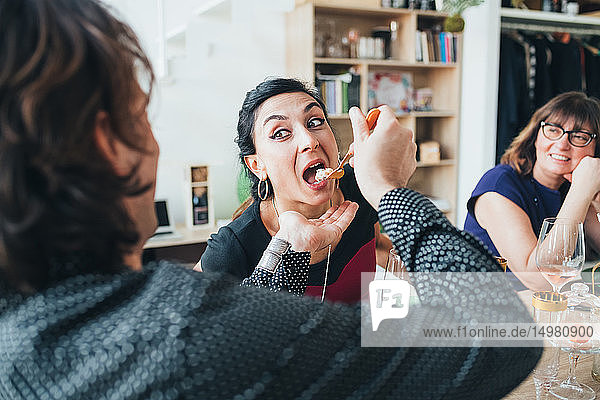 Man feeding woman at lunch party in loft office