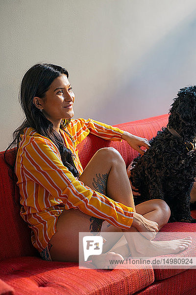 Hipster-Frau mit Haushund auf Sofa