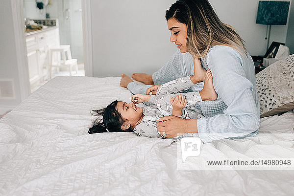Girl lying by mother on bed in morning