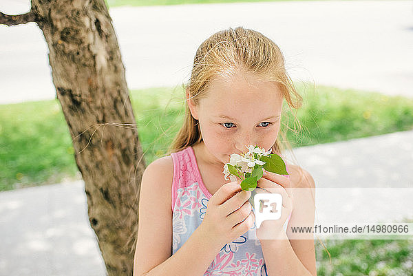 Mädchen riecht Blüte in einer Vorstadtstraße