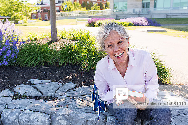 Senior woman sitting on park rockery  portrait