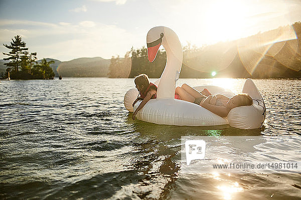 Girls playing on inflatable swan in lake