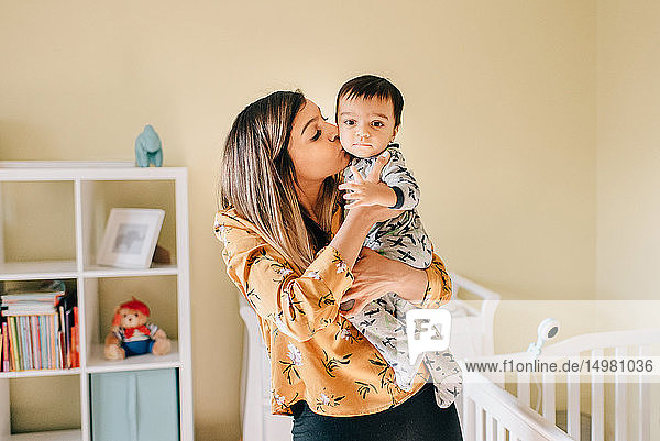 Mutter küsst ihren kleinen Sohn im Kinderzimmer  Porträt