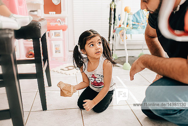 Mädchen wischt den Küchenboden  Vater schaut zu