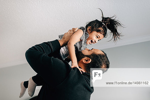 Girl being held up by father  side view