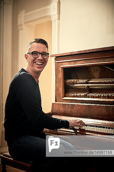 Mann grinst und spielt Klavier