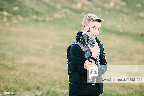 Boy carrying puppy outdoors