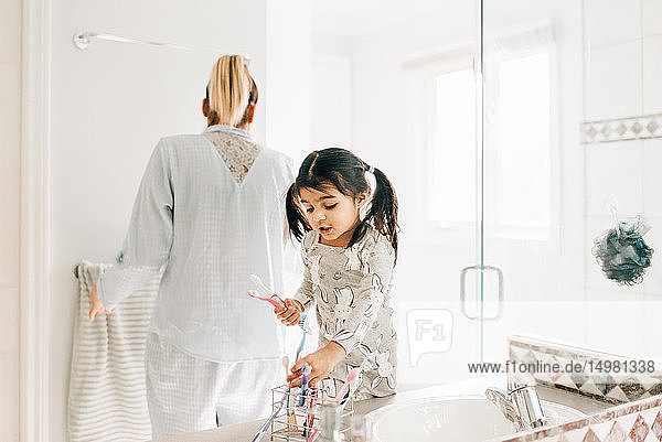 Mädchen mit Mutter wählt Zahnbürste im Badezimmer