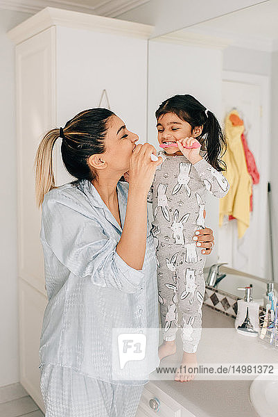 Mädchen und Mutter beim Zähneputzen im Badezimmer