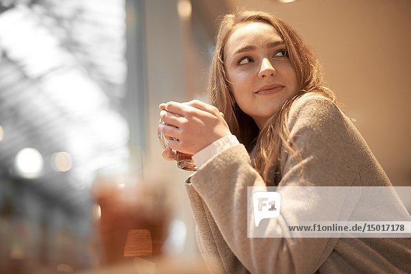 Young woman with warm tea in hands  indoors in café  in Cottbus  Brandenburg  Germany